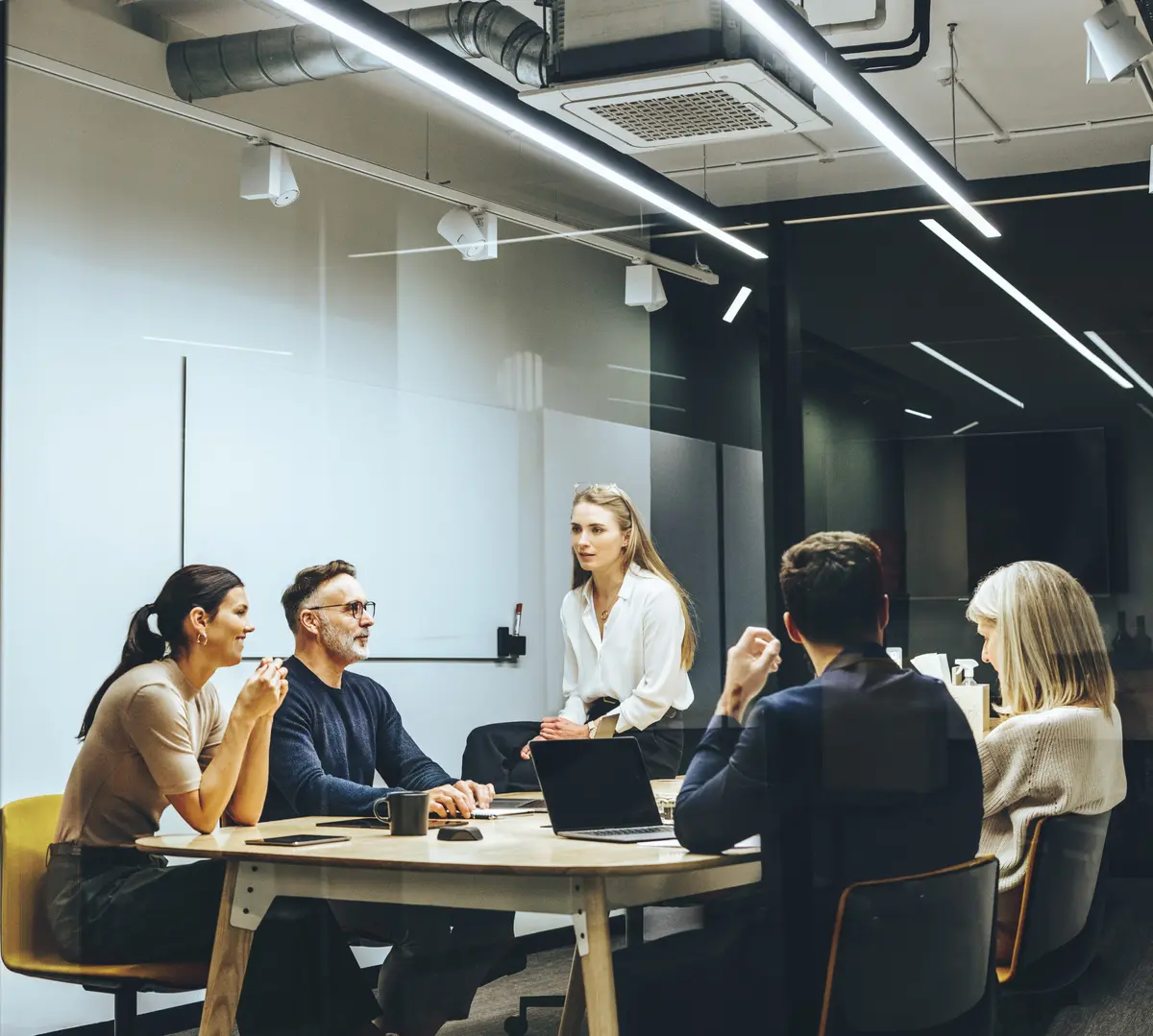 réunion d’équipe dans une salle de travail moderne et épurée, avec six coworkers en pleine discussion autour d’une table ronde